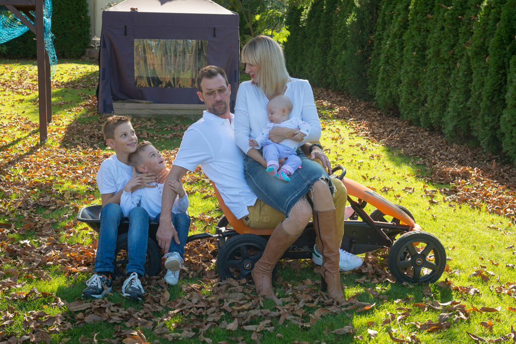 Die ganze Familie sitzt auf dem Kettcar mit Anh&auml;nger, Lustiger Familienmoment Outdoor Familienfoto Bietigheim-Bissingen