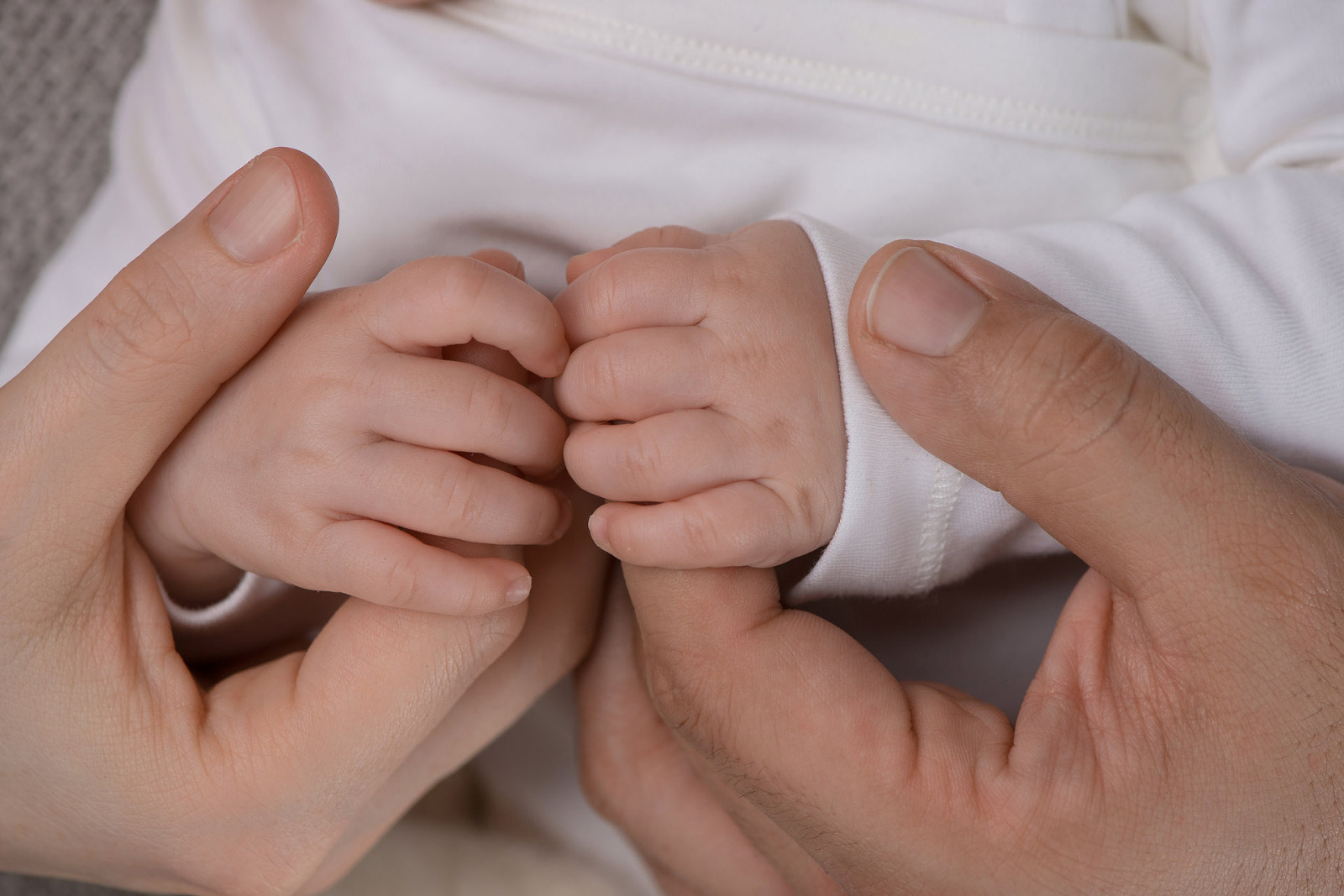 Hände Eltern die die Hände eines Babys festhalten
