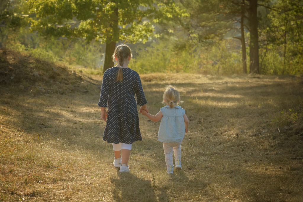 Schwestern halten sich an den H&auml;nden und laufen einen weg entlang Gegenlicht