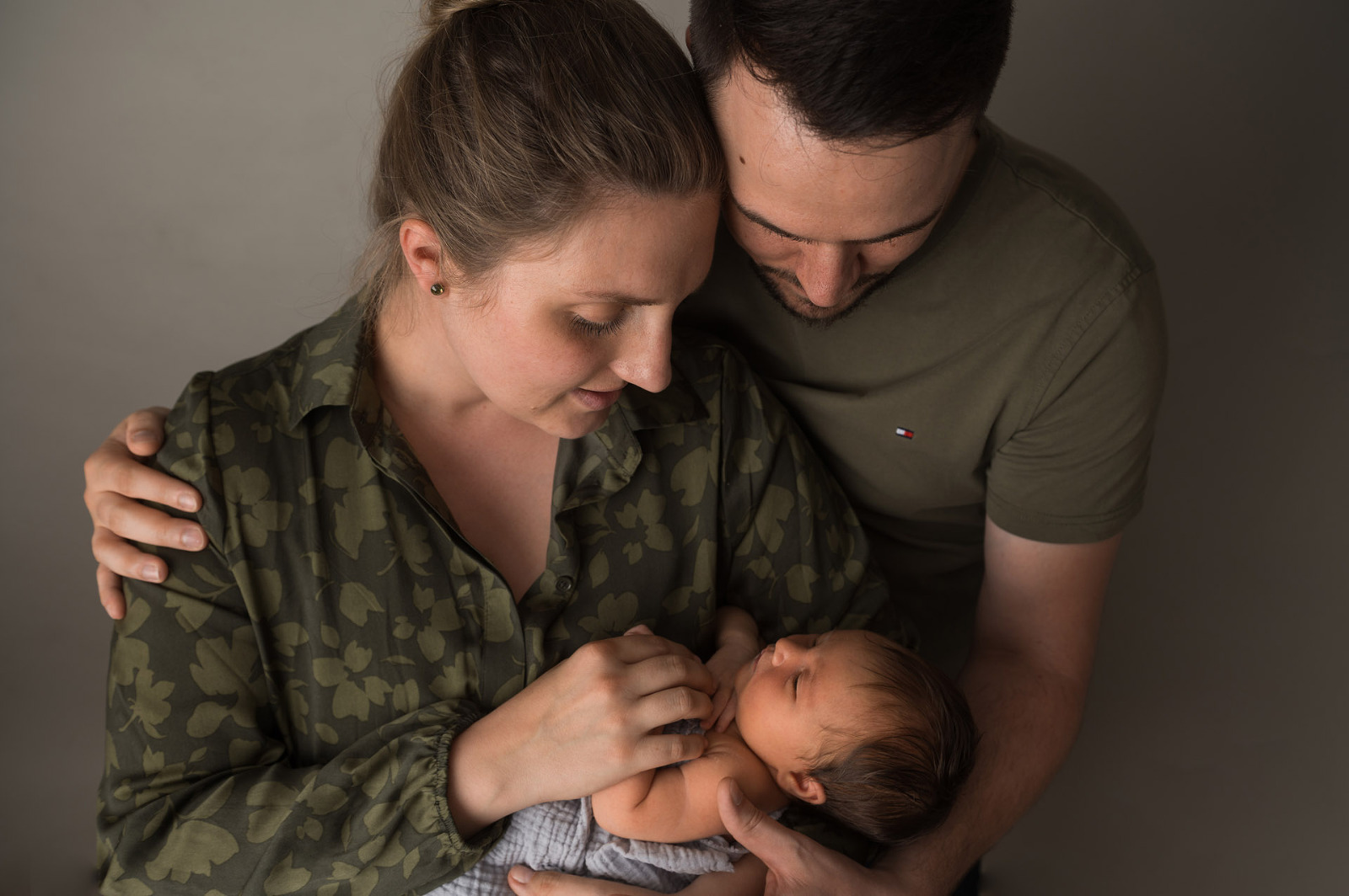 Eltern kuscheln mit Baby auf dem Arm