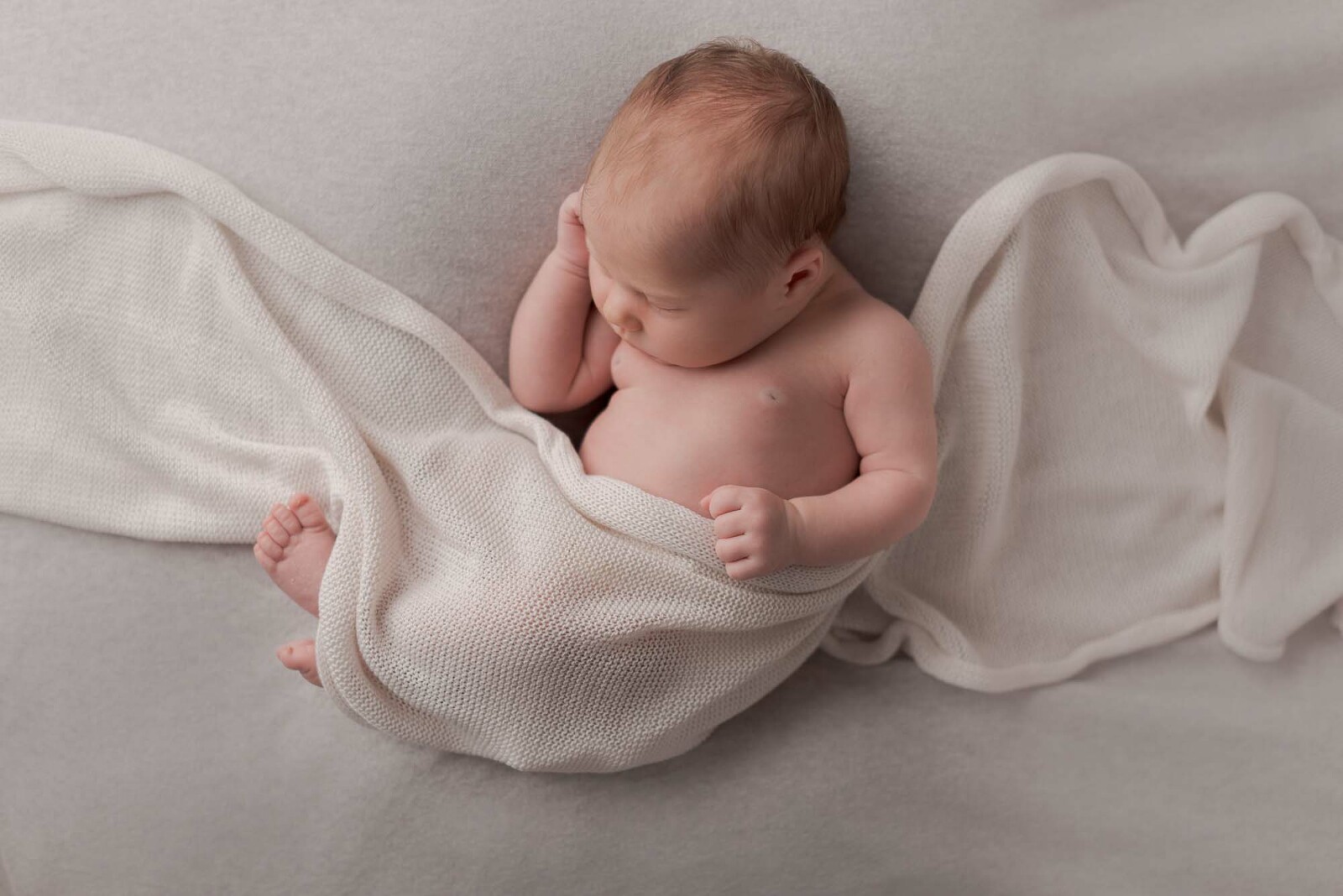 Babyfotos Baby kuschelt sich in ein Tuch