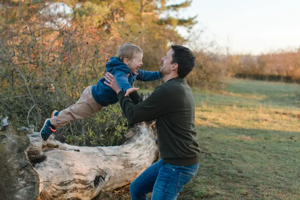 Kind h&uuml;pft lachend in die Arme des Vaters, liebevolle Familienaufnahme Outdoor Sersheim