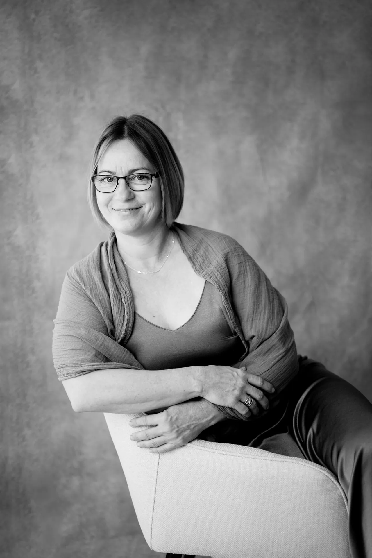 Natürliches Frauenporträt im Studio – sitzende Pose im grauen Kleid