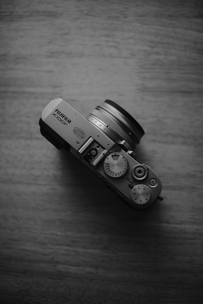 Black and white photo of a vintage-style digital camera from above on wooden table.