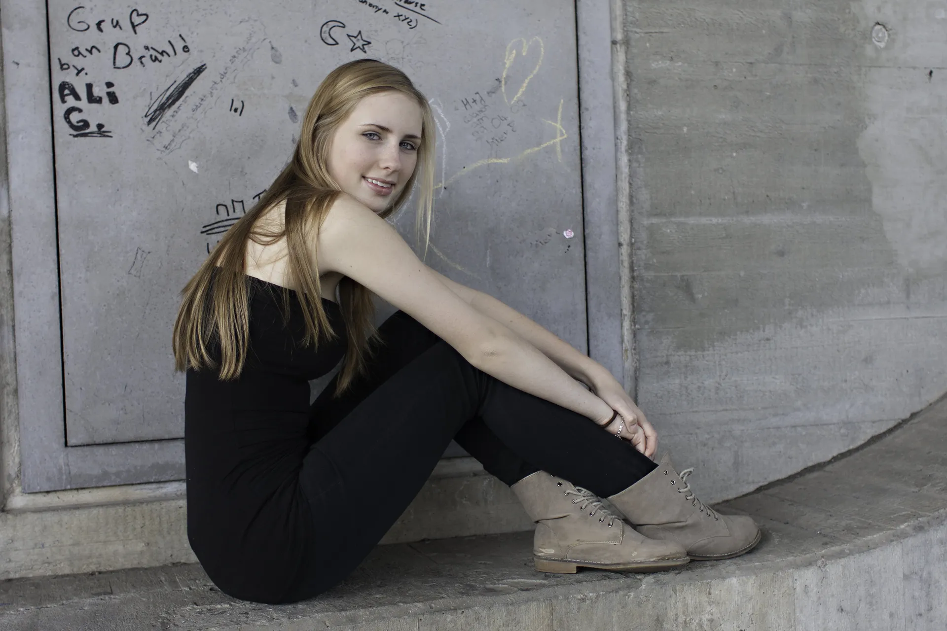 junge Frau mit langen blonden Haaren Hand in urbanen Umgebung sitzend - color
