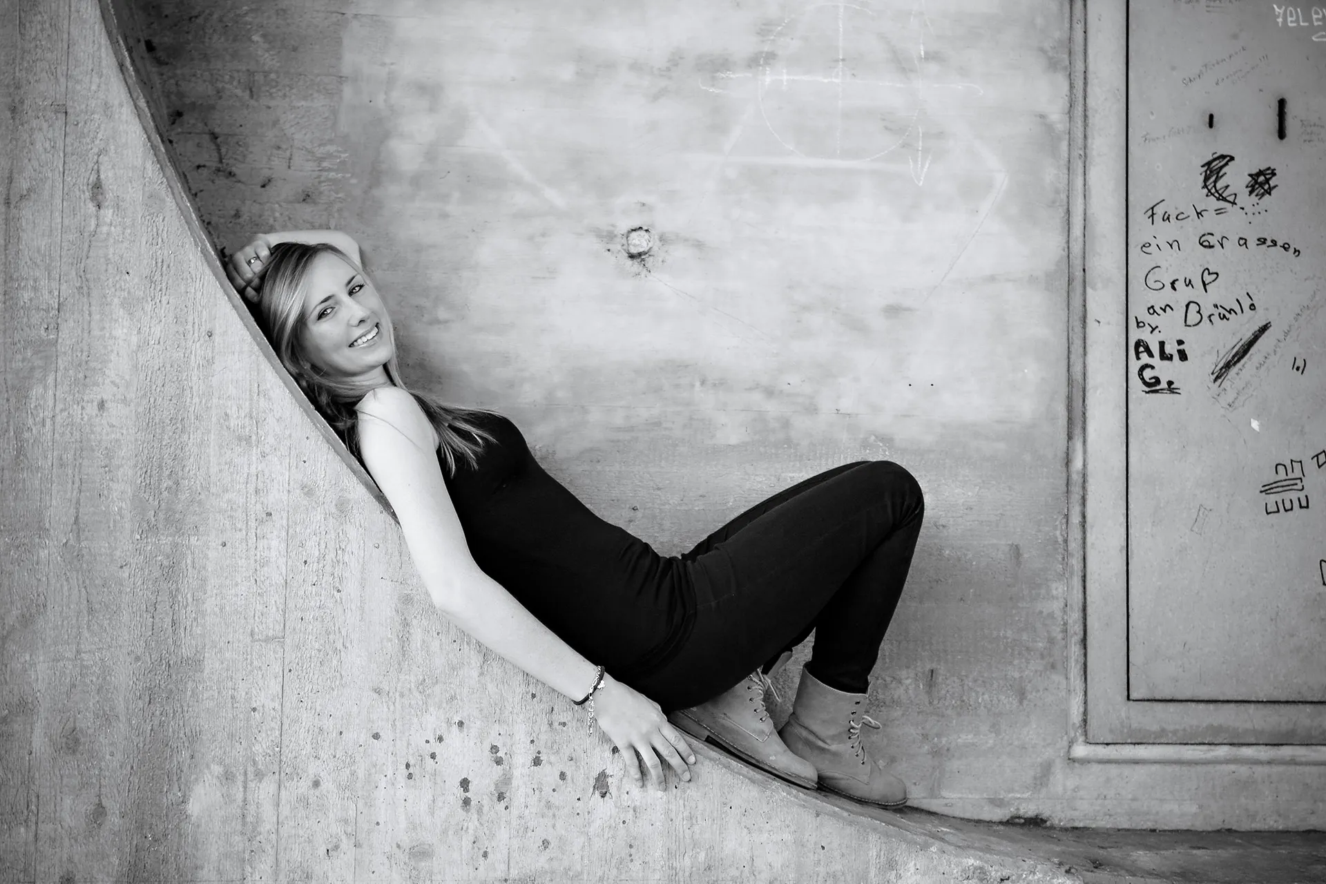 junge Frau mit langen blonden Haaren Hand &uuml;ber den Kopf gelegt liegend in urbanen Umgebung Schwarzwei&szlig;