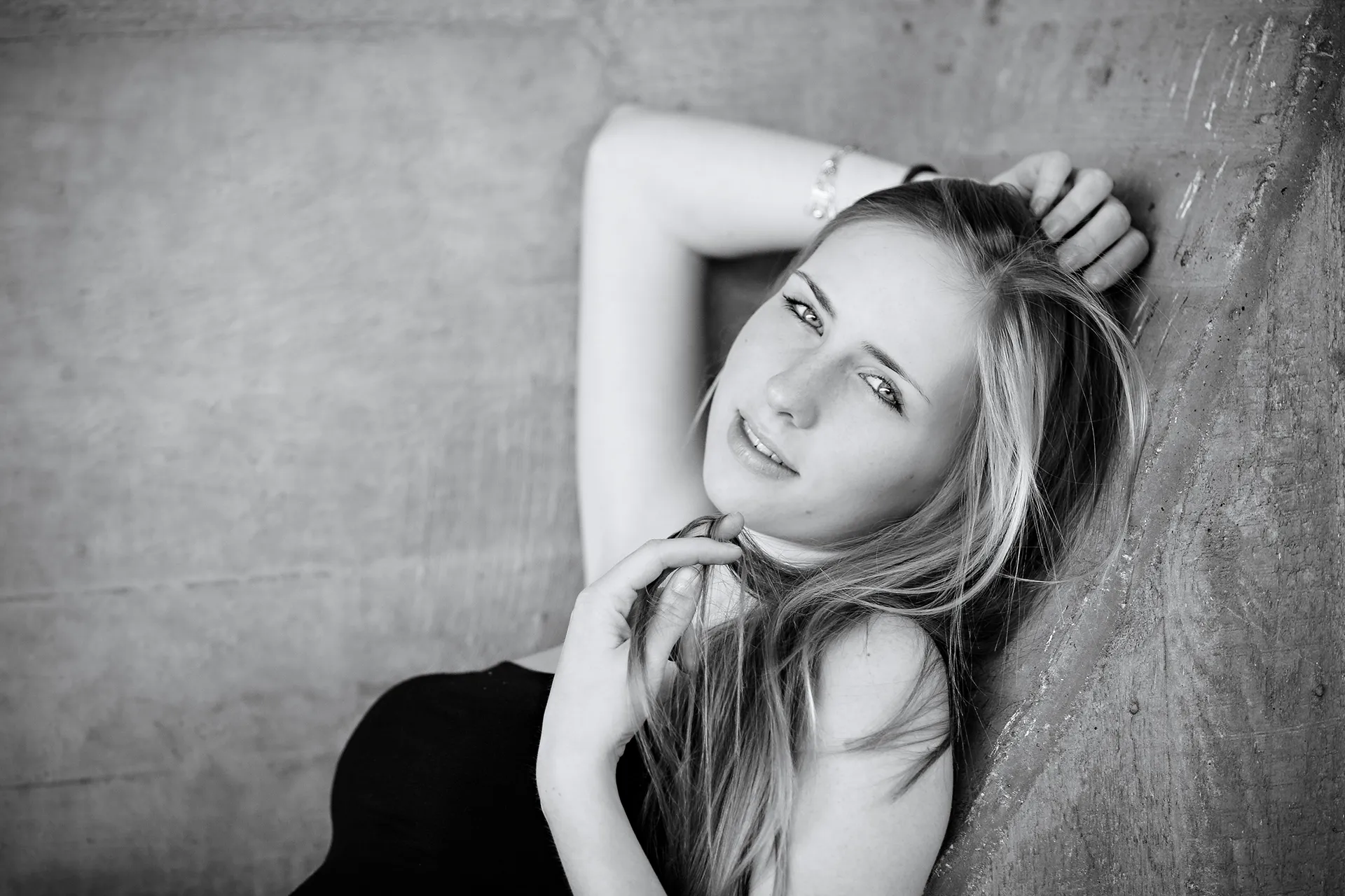 sanft l&auml;chelnde junge Frau mit langen blonden Haaren, liegend, Schwarzwei&szlig;