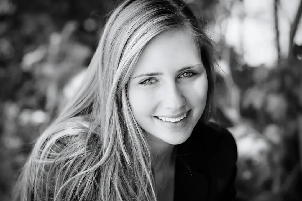 Junge Frau mit langen blonden Haaren, sitzend, sympathisch lächeld, sanftes Licht - SW