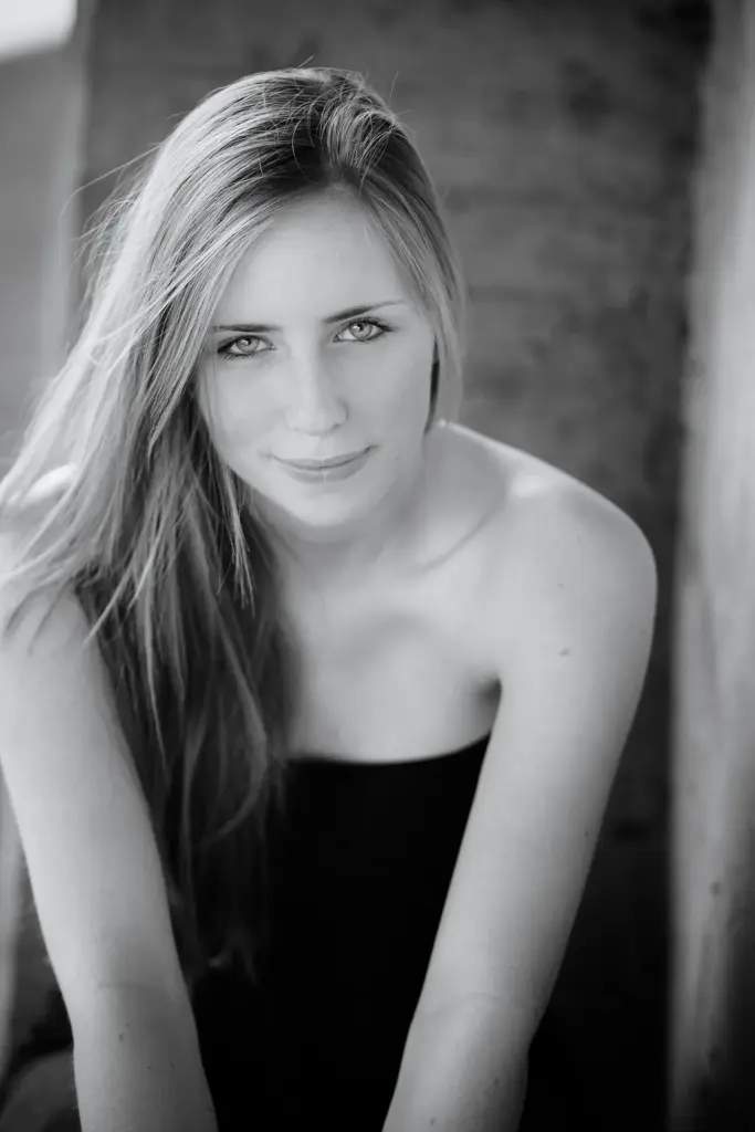 Junge Frau mit langen blonden Haaren, sitzend, ruhige Pose, sanftes Licht in sw