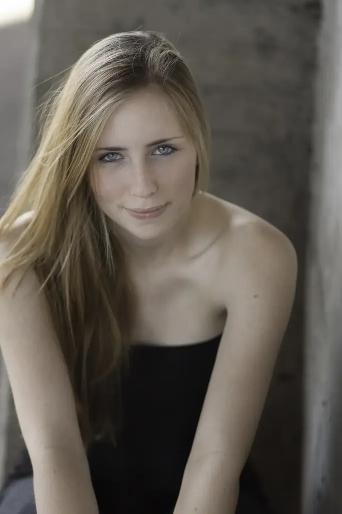 Junge Frau mit langen blonden Haaren, sitzend, ruhige Pose, sanftes Licht - color